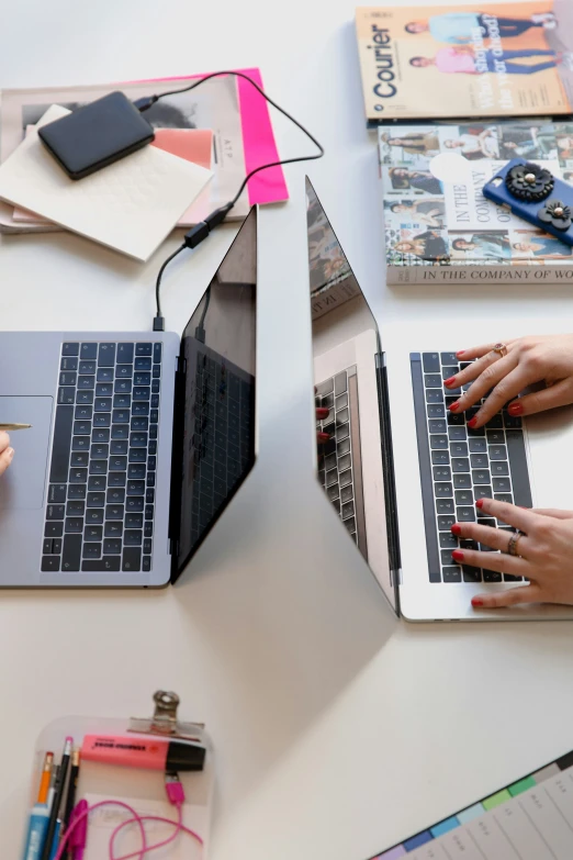 two open laptop computers sitting on a white desk