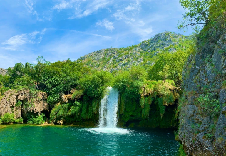 waterfall in blue lake with blue sky and clouds