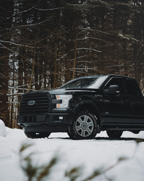 an suv parked on snow covered ground in front of a forest