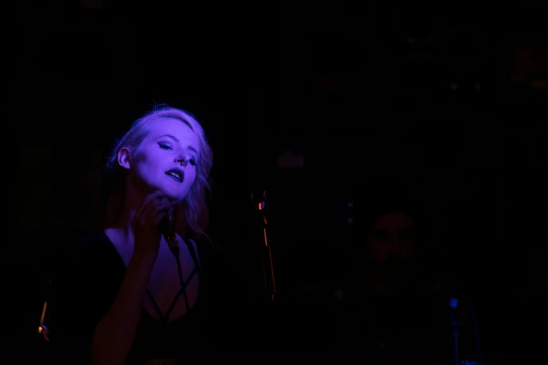 a woman with dark makeup and microphone in the dark