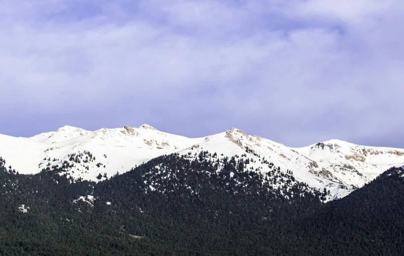 a snow covered mountain range during a cloudy day