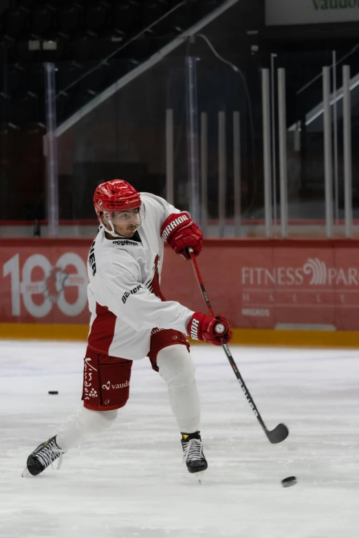 a hockey player wearing red and white with a hockey stick