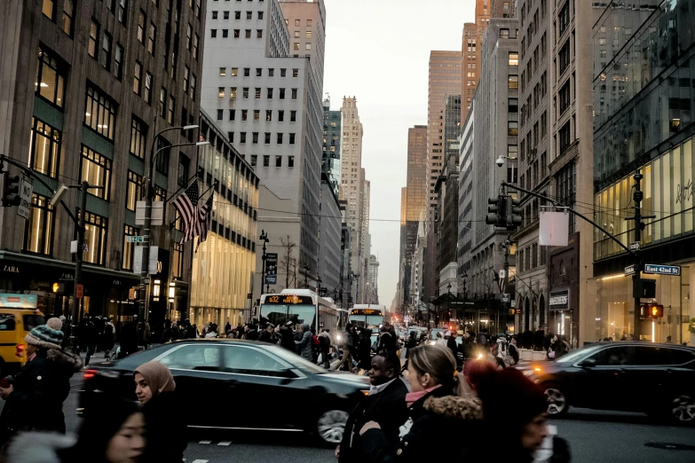 an intersection with many cars, and a lot of people walking through the street