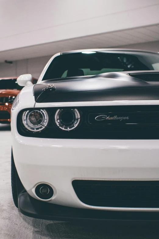 the front end of a white dodge car in a garage