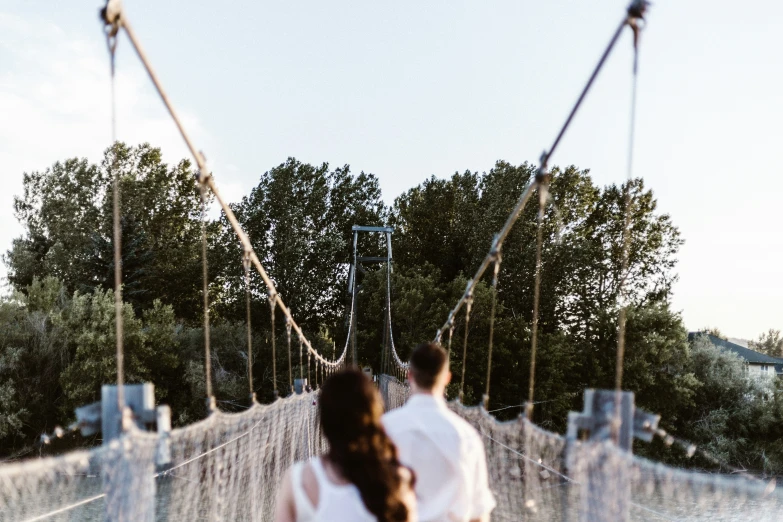 a couple walking on a bridge with ropes to walk along