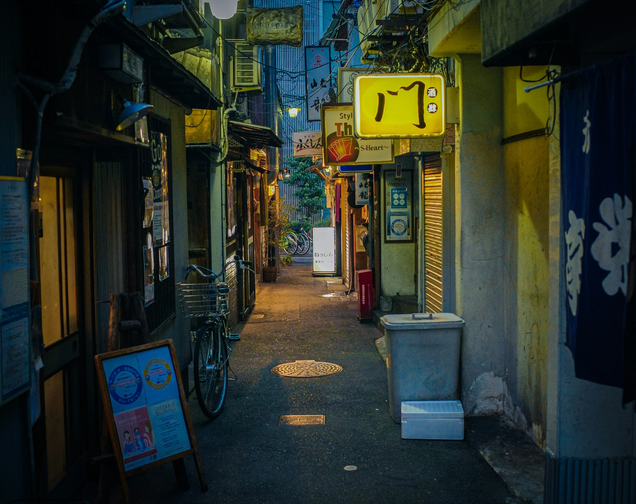 a narrow alley with signs and bicycles parked outside