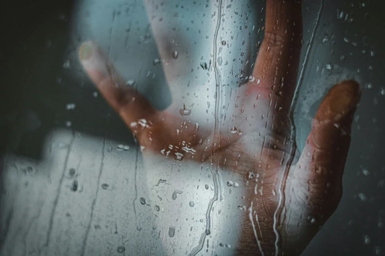 a hand holding out their left hand through the glass