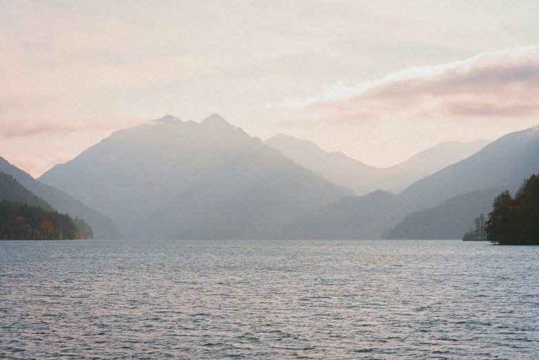 a boat floats across the calm waters between mountains