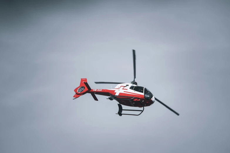 red helicopter flying through the sky with four blades