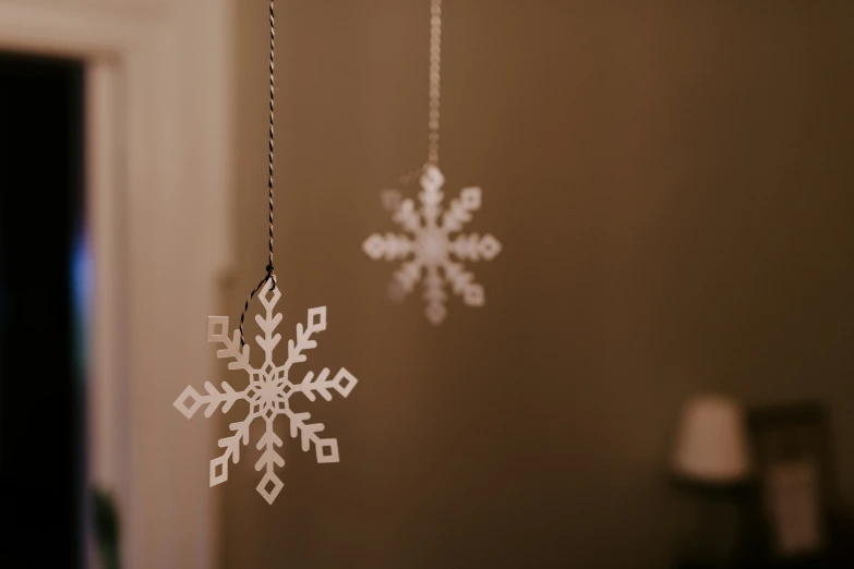 white hanging ornaments with snowflakes on them hanging from strings