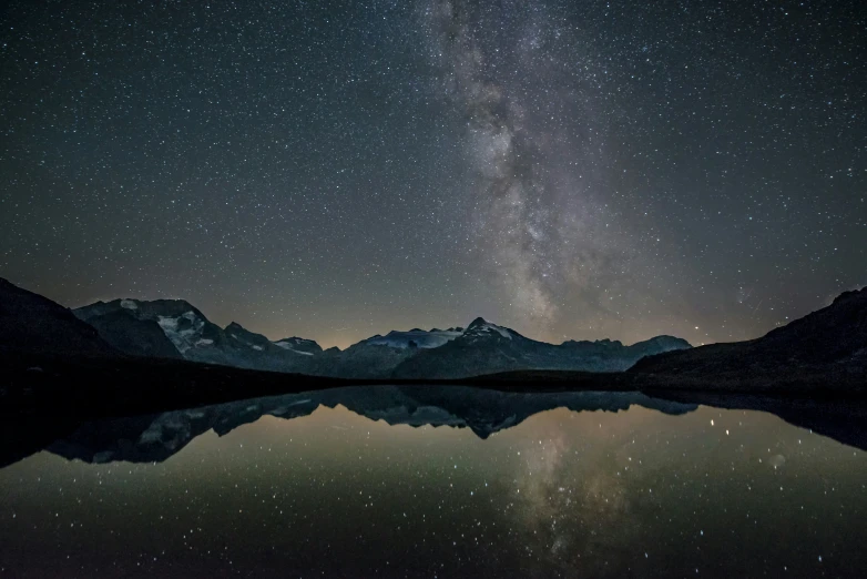 a lake is surrounded by mountains and the milky