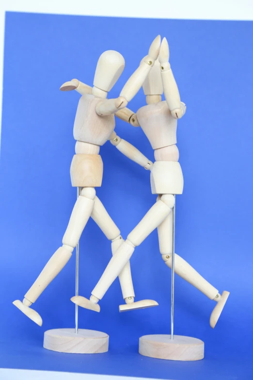 two wooden mannequins are touching each other with their arms