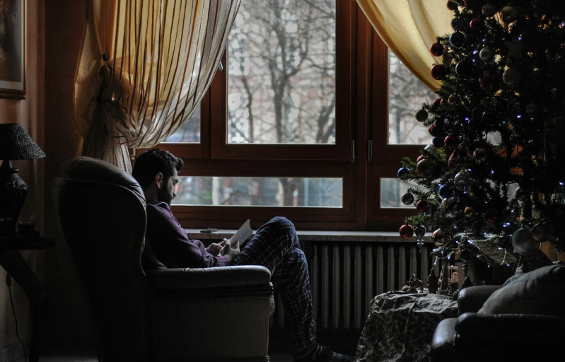 a person sitting in a chair next to a christmas tree