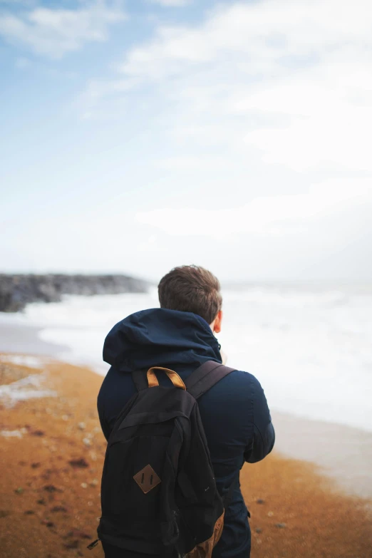 a person in a blue jacket on the beach