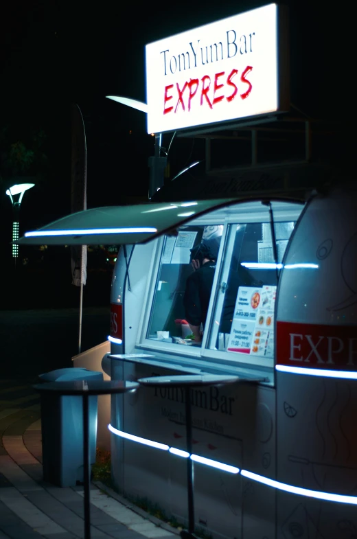 a man sitting inside of a restaurant that is lit up with neon lights