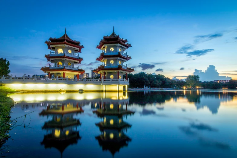 two chinese styled buildings are shown with water reflecting them