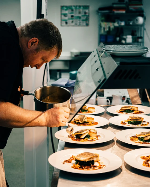 a person cooking in the kitchen near many plates