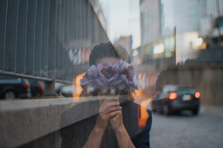 a man in blue shirt holding flowers by wall