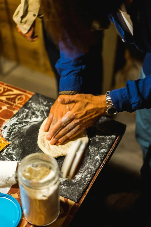 a man kneads dough with his hands on top