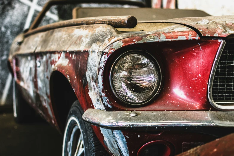 an old ford mustang, with rust, is on display