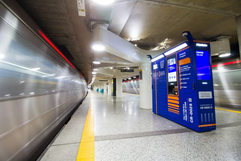 an empty subway station with a blue and orange phone booth