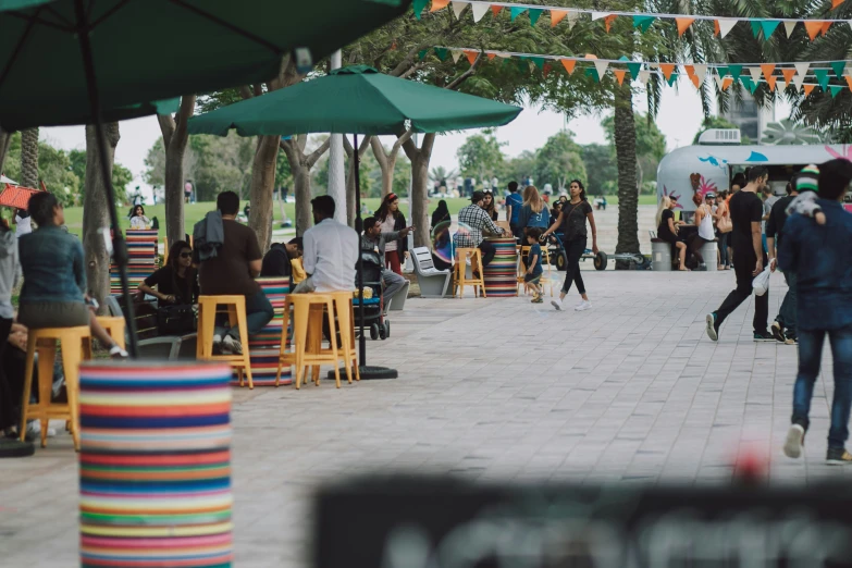 people are gathered at tables and umbrellas on a boardwalk