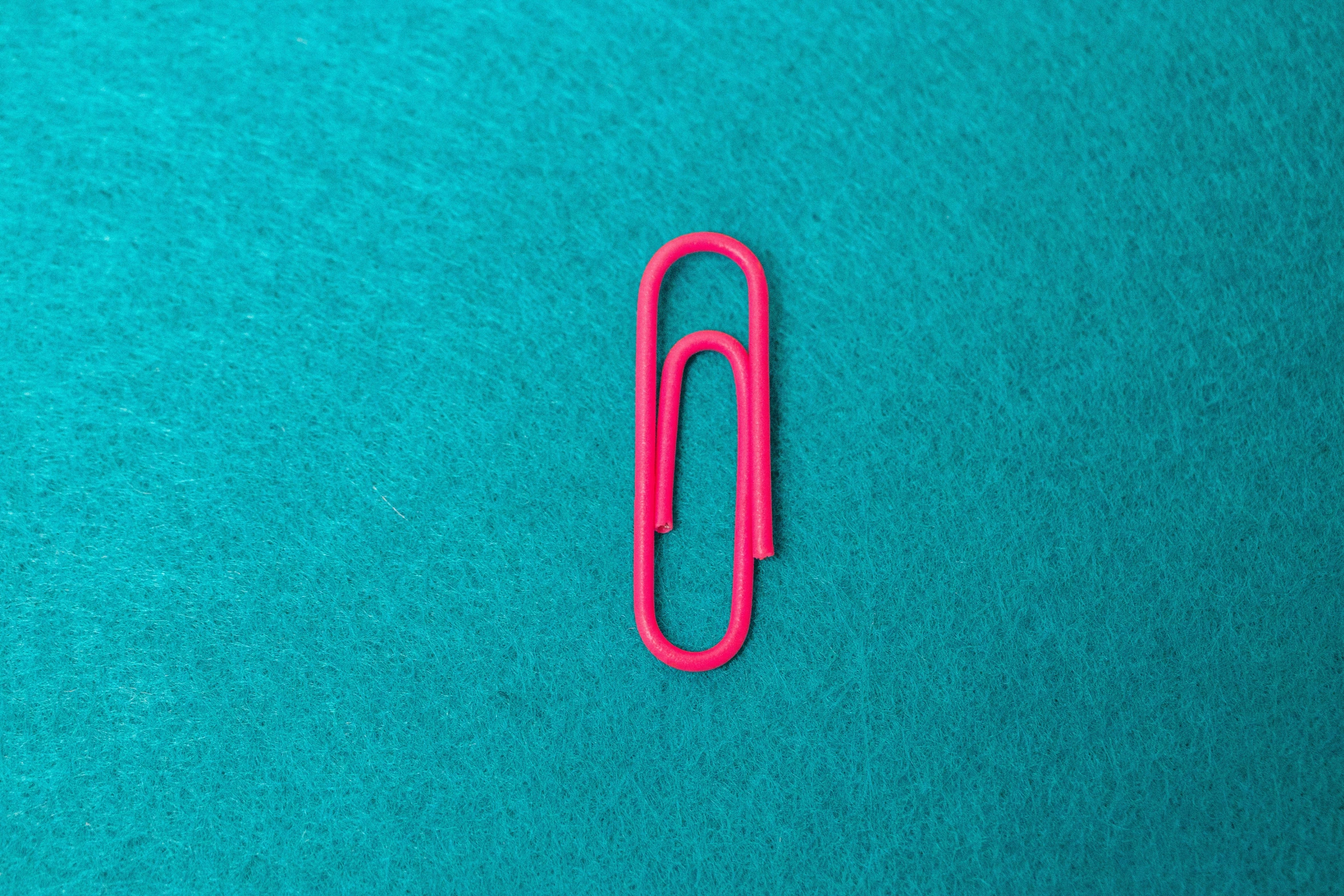 an orange paper clip is laying on the green material