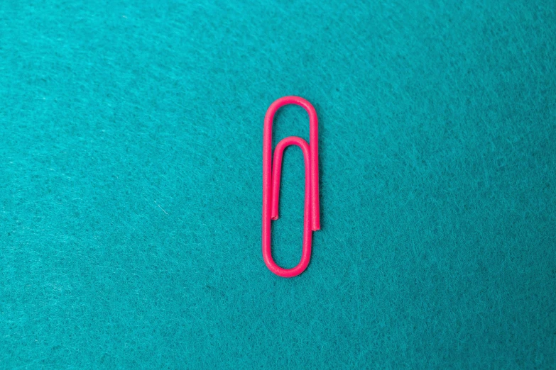 an orange paper clip is laying on the green material