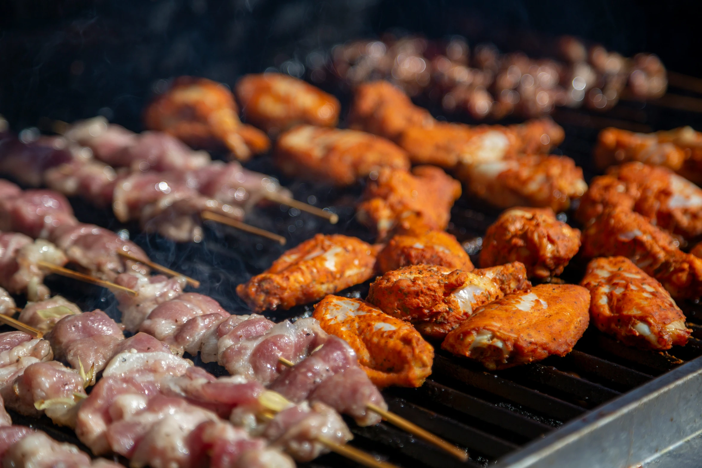 a charcoal grill with various skewers of food being grilled