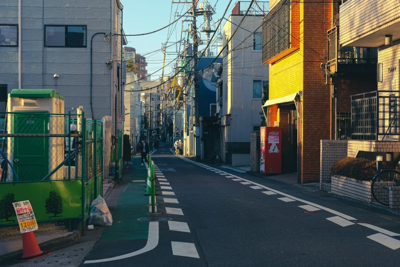 a narrow city street with houses, fences and signage on the buildings