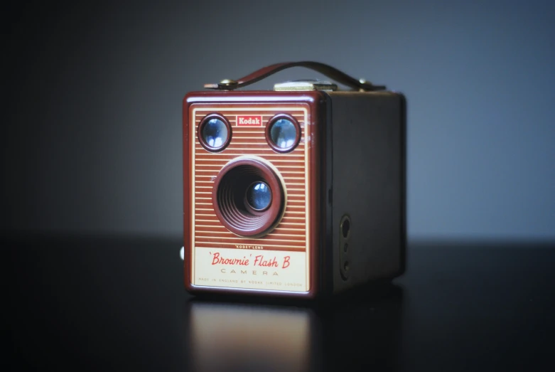 an old fashioned camera sitting on top of a wooden table