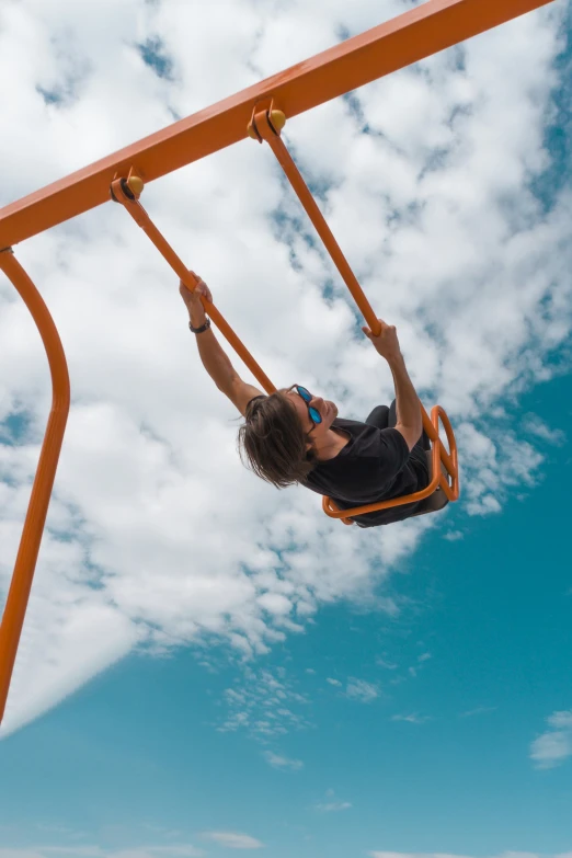 a woman is swinging on a metal swingset