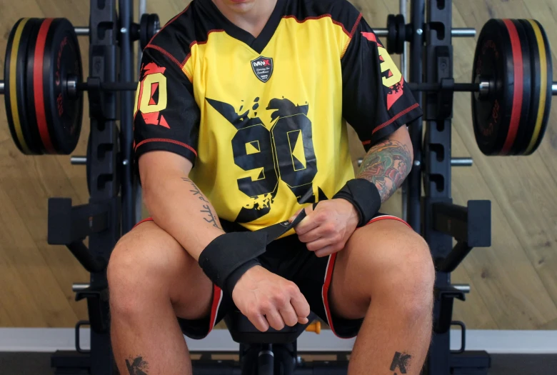 a man wearing glasses sitting on a bench next to a gym rack