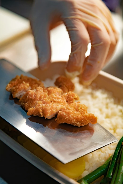 a hand reaching for a piece of fried food
