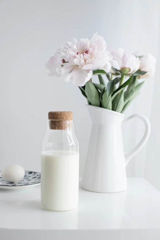 a bottle of milk and a jar filled with white flowers