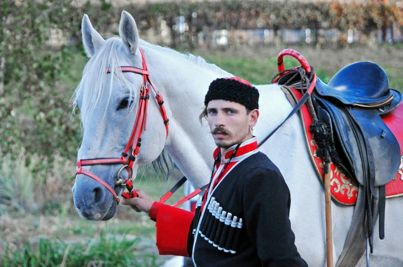 a man standing next to a white horse