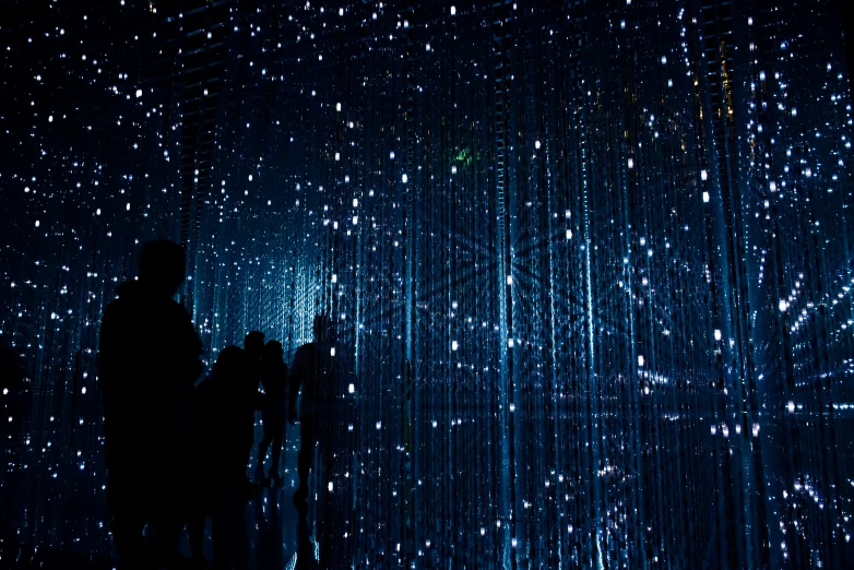 people stand in front of a projection wall on which are falling rain drops