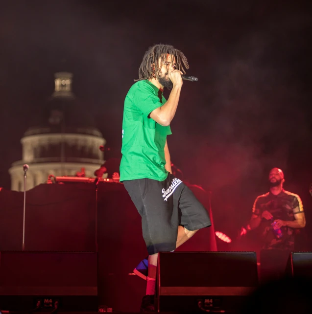 a male in a green shirt is singing on stage