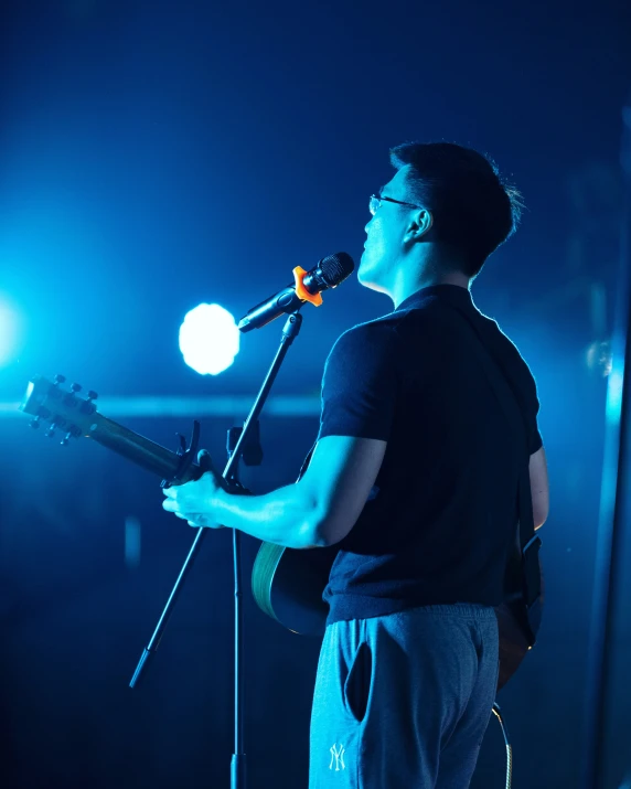 a man holding a microphone while standing in front of a microphone