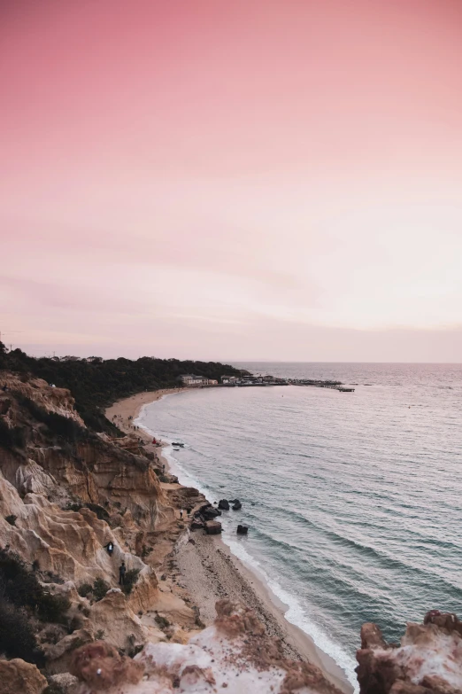 an ocean line and rocky cliff side with the sun in the sky