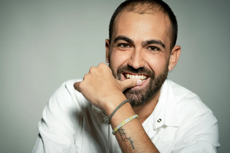 a smiling man is wearing a celet and has a watch on his wrist