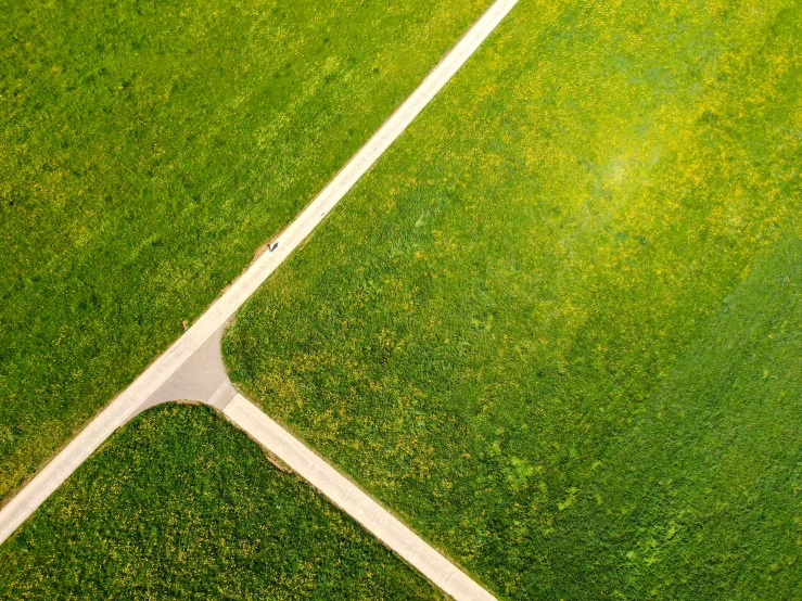 aerial view of a road crossing across a green field