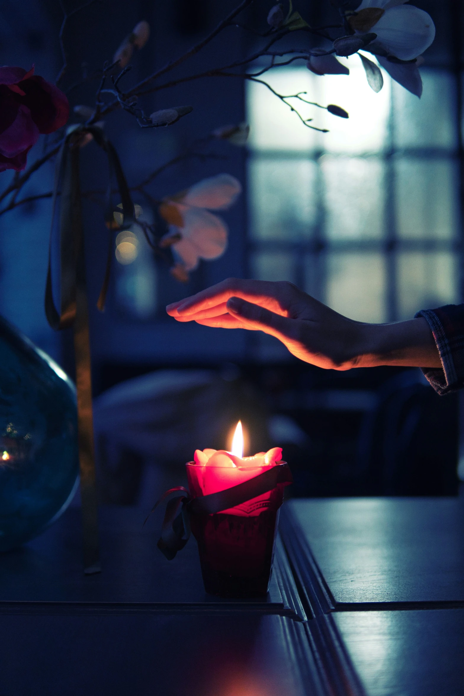 someone holding a lit candle next to their reflection