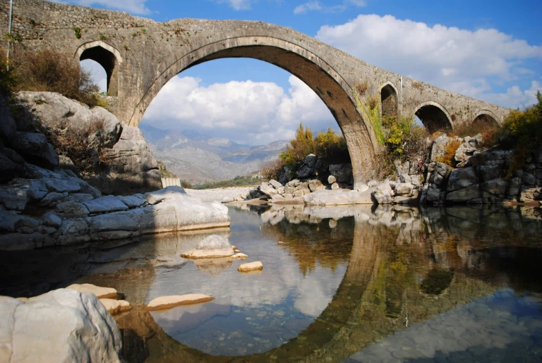 an old stone bridge spanning a narrow body of water