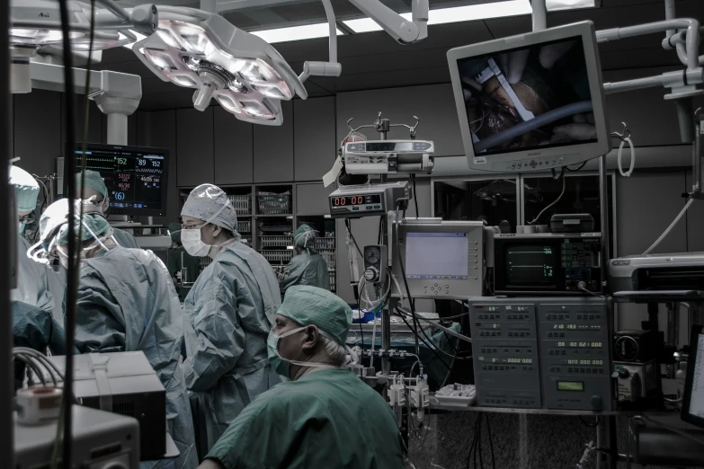 three surgeons are in a large operating room