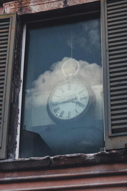 a clock is seen through a window with shutters