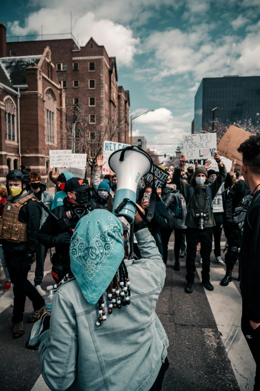 a woman wearing a mask holds up her hand in a crowd