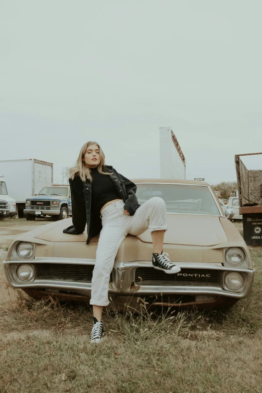 a woman sitting on the hood of a car