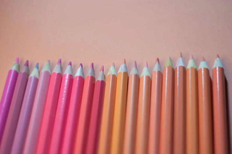 colored pencils lined up on a pink background