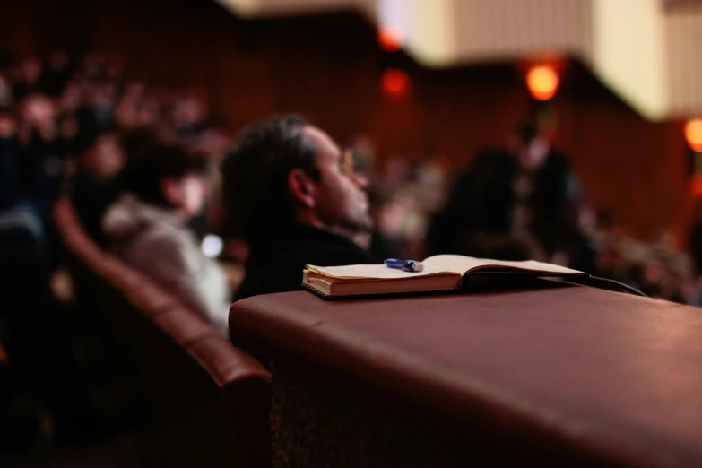 a man staring away from the group while holding a book